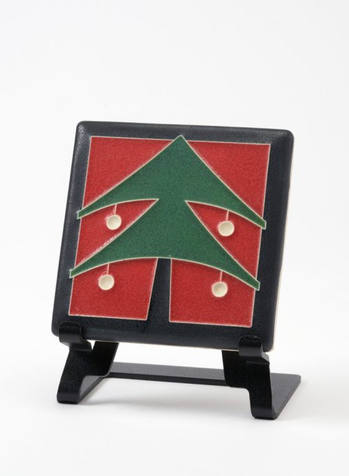A ceramic art tile by Motawi Tileworks featuring a Christmas a green Christmas tree with a red background.